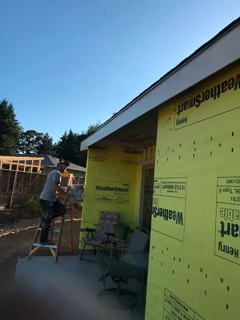 Yellow house wrap and fresh white eaves, mid-job