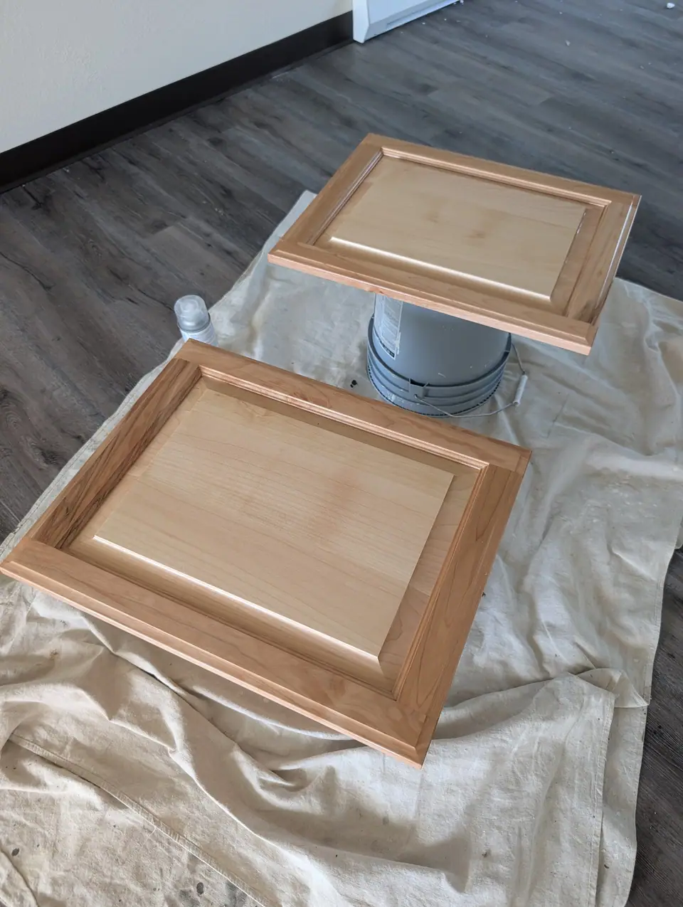 Two cabinet doors laid out on drop cloths, freshly finished