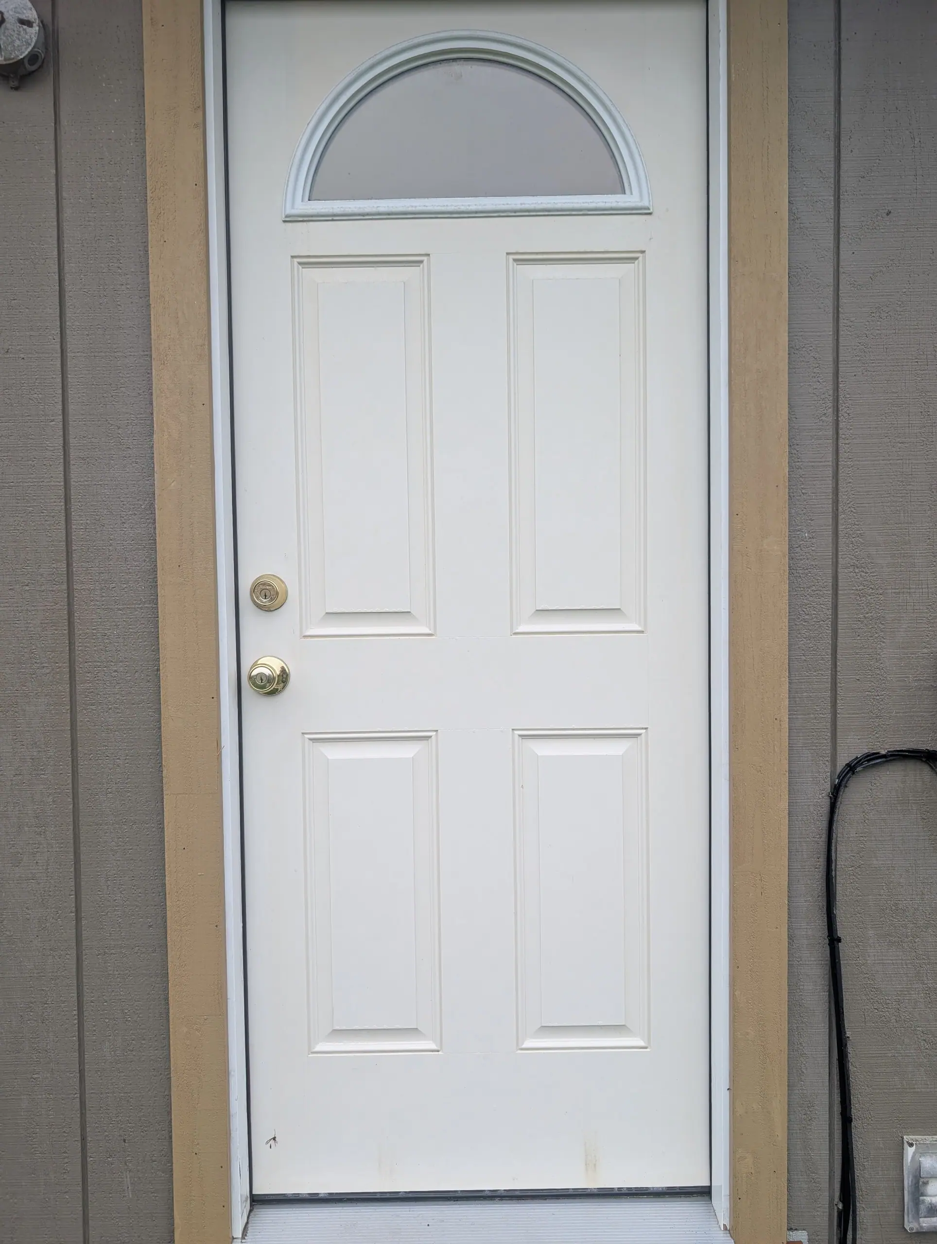 A new white six-panel exterior door with a half-round window