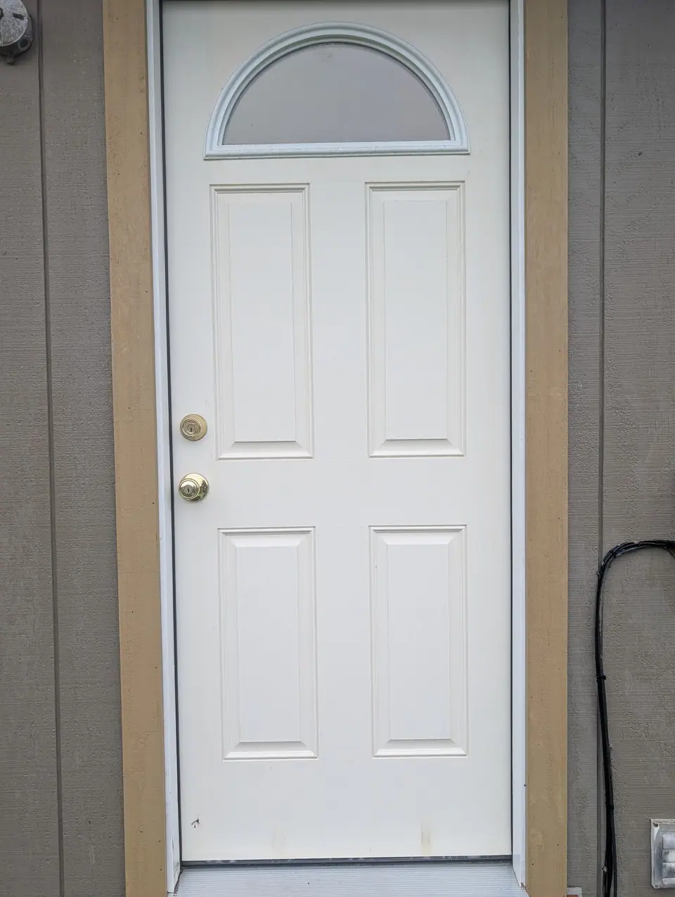 A new white six-panel exterior door with a half-round window