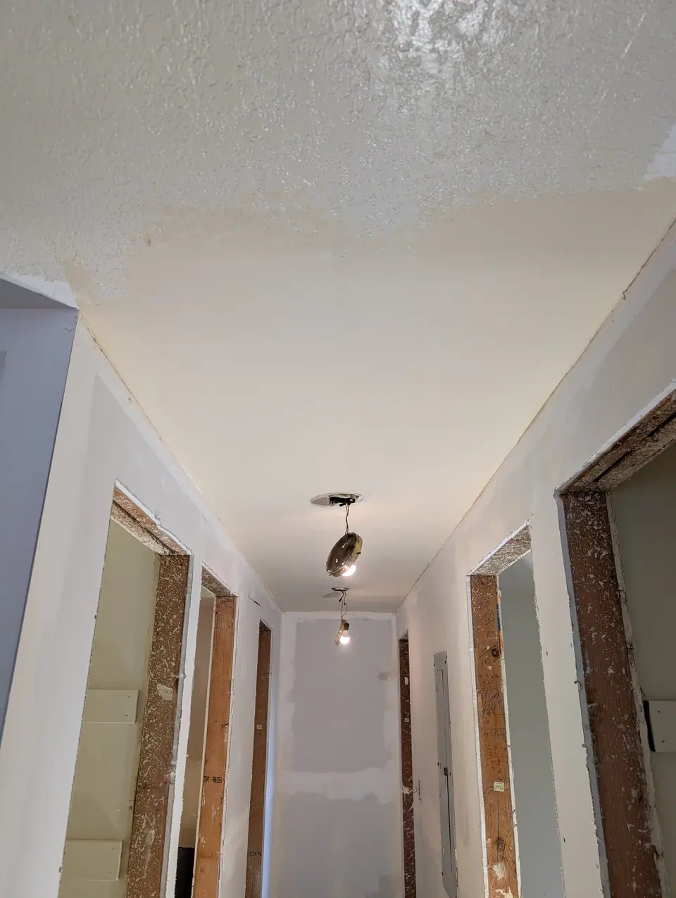 A hallway with new drywall and bare door frames during a rehab
