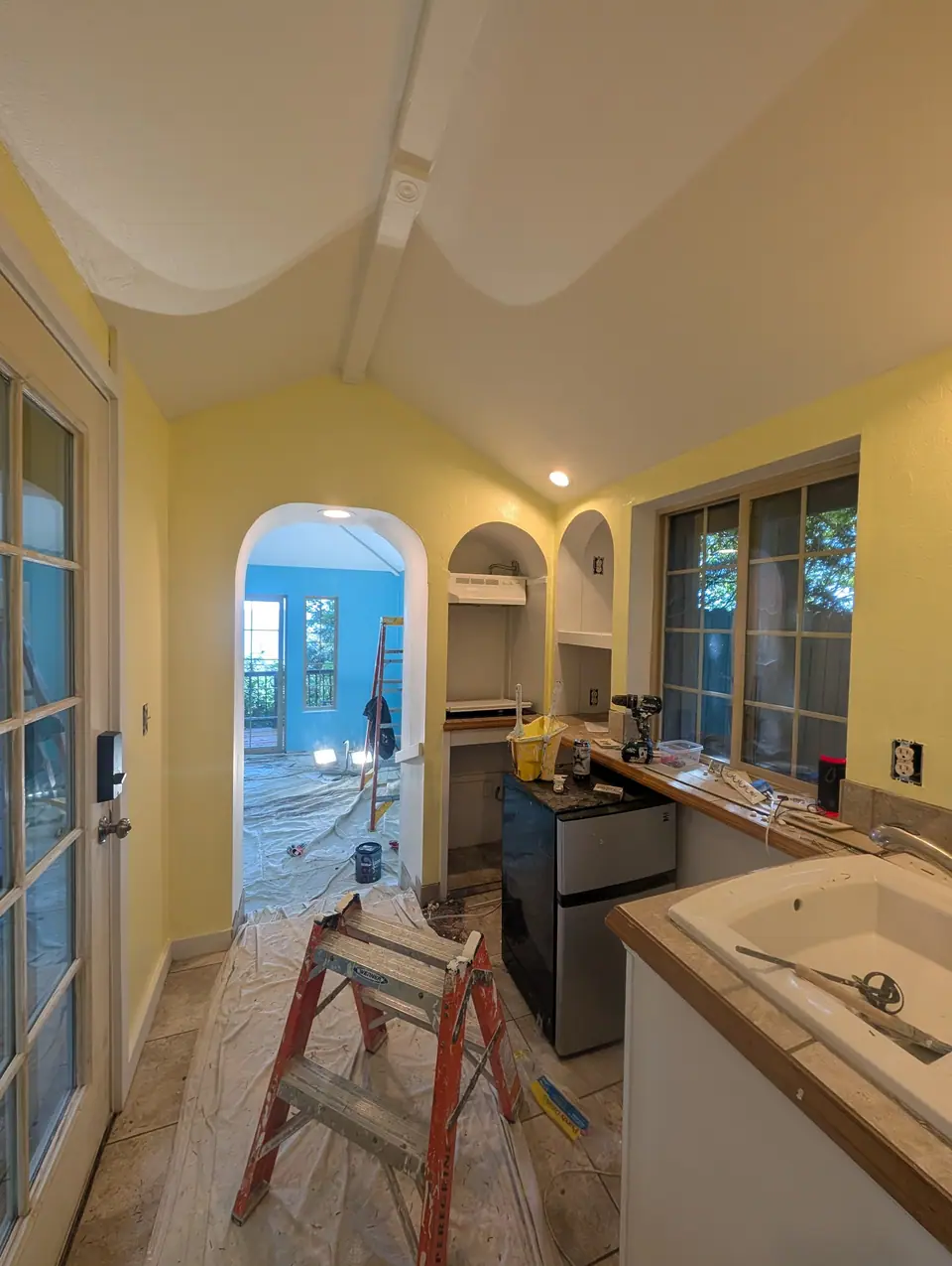 A narrow yellow kitchen with an arch through to the blue room