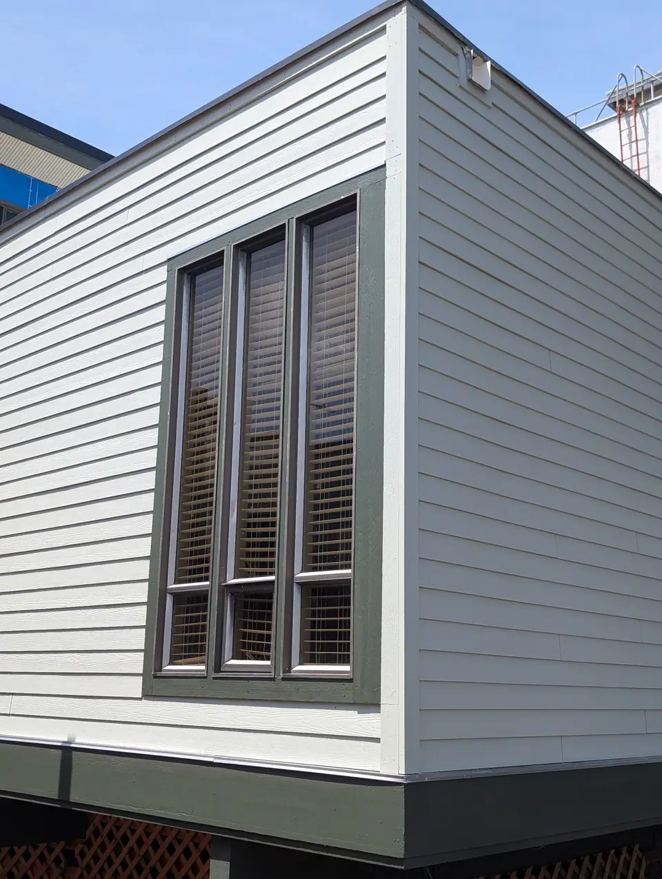 A corner of the commercial building: gray siding, dark window trim and skirting